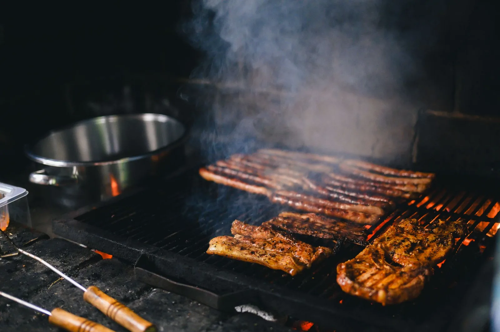 Built-in gas grill with glowing ceramic burners in an outdoor kitchen